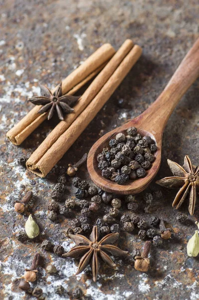 Baharatlar ve bitkiler. Yiyecek ve mutfak malzemeleri. Tarçın çubukları, anason yıldızları, karabiber ve dokulu arka planda kakule..