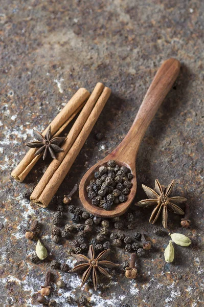 Baharatlar ve bitkiler. Yiyecek ve mutfak malzemeleri. Tarçın çubukları, anason yıldızları, karabiber ve dokulu arka planda kakule..
