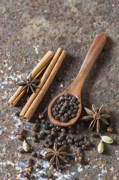 Kruiden en kruiden. Voedsel en keuken ingrediënten. Kaneelstokjes, anijssterren, zwarte peperkorrels en kardemom op een getextureerde achtergrond. — Stockfoto