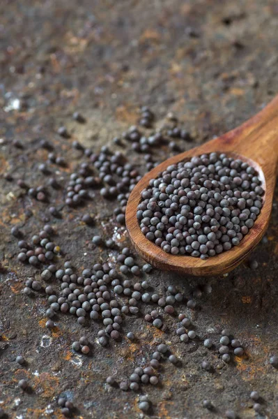 Brown Mustard Seeds in wooden spoon on a textured background — Stock Photo, Image