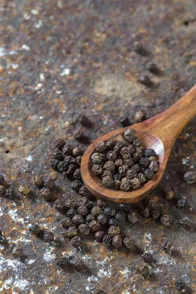 Peppercorns in wooden spoon on texture background — Stock Photo, Image