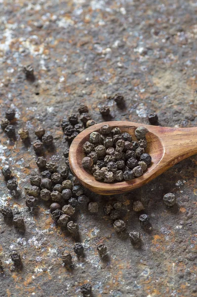 Peppercorns in wooden spoon on texture background — Stock Photo, Image