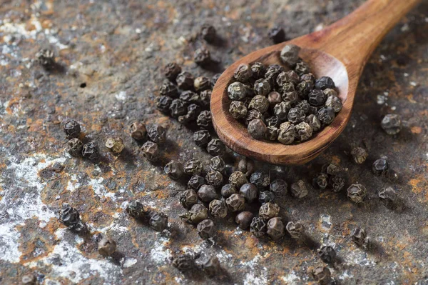 Peppercorns in wooden spoon on texture background — Stock Photo, Image