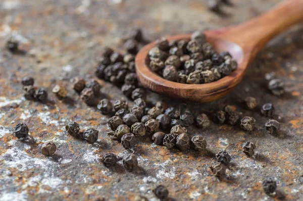 Peppercorns in wooden spoon on texture background — Stock Photo, Image