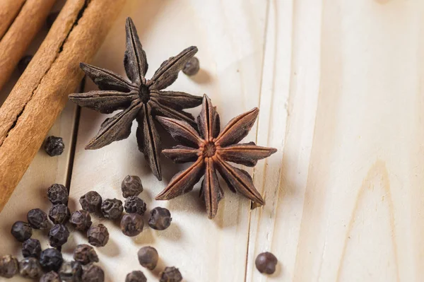 Kruiden en kruiden. Voedsel en keuken ingrediënten. Kaneelstokjes, anijssterren en zwarte peperkorrels op een houten ondergrond. — Stockfoto