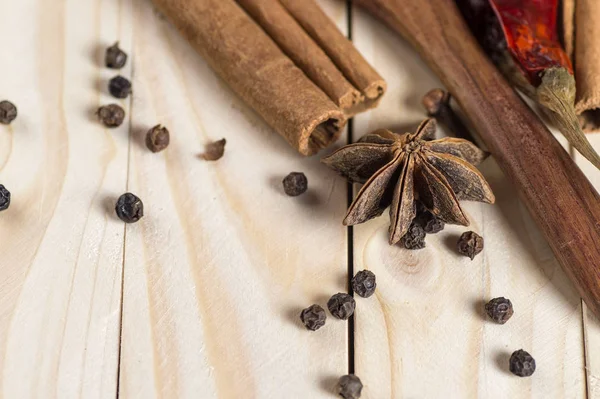 Kruiden en kruiden. Voedsel en keuken ingrediënten. Kaneelstokjes, anijssterren, zwarte peperkorrels, Chili, Kardemom en Kruidnagel op een houten ondergrond — Stockfoto