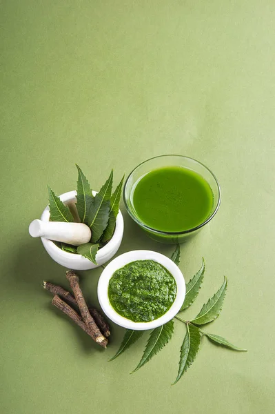 Yeşil zemin üzerine harç ve havaneli neem Yapıştır, suyu ve dallar ile tıbbi Neem yaprağı