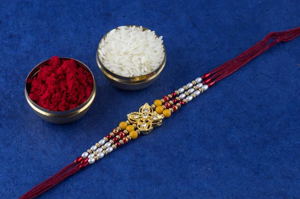 Festival indio: Raksha Bandhan fondo con un elegante Rakhi, granos de arroz y Kumkum. Una pulsera india tradicional que es un símbolo de amor entre hermanos y hermanas. —  Fotos de Stock