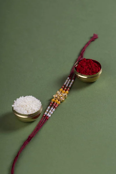 Festivalul indian: Raksha Bandhan fundal cu un elegant Rakhi, cereale de orez și Kumkum. O trupă tradițională indiană de încheietură a mâinii, care este un simbol al iubirii dintre frați și surori . — Fotografie, imagine de stoc