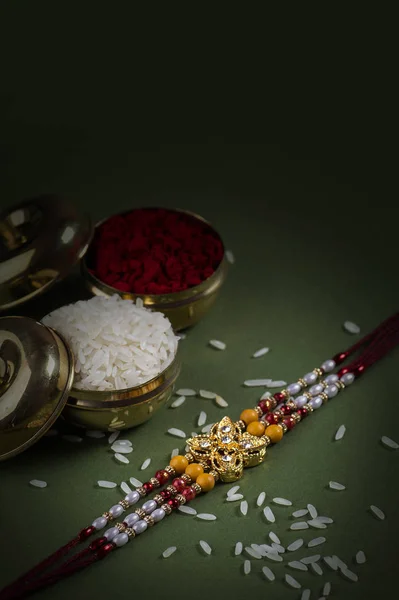 Festivalul indian: Raksha Bandhan fundal cu un elegant Rakhi, cereale de orez și Kumkum. O trupă tradițională indiană de încheietură a mâinii, care este un simbol al iubirii dintre frați și surori . — Fotografie, imagine de stoc