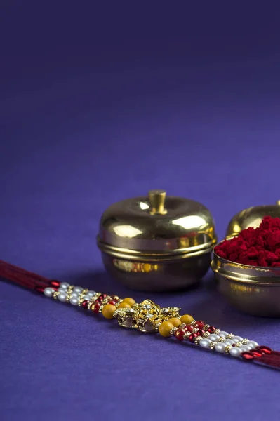 Festivalul indian: Raksha Bandhan fundal cu un elegant Rakhi, cereale de orez și Kumkum. O trupă tradițională indiană de încheietură a mâinii, care este un simbol al iubirii dintre frați și surori . — Fotografie, imagine de stoc