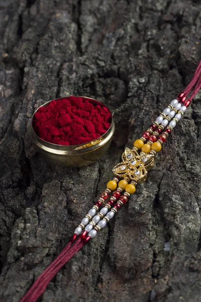 Indiska festival: Raksha Bandhan bakgrund med en elegant Rakhi, Rice Grains och Kumkum. Ett traditionellt indiskt armband som är en symbol för kärlek mellan bröder och systrar. — Stockfoto