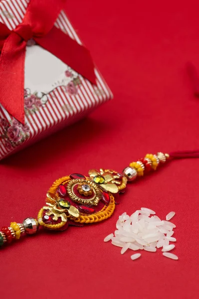 Raakhi y un regalo para la hermana dado por el hermano con motivo de Raksha Bandhan. Festival indio Raksha Bandhan fondo con un elegante Rakhi sobre fondo rojo . — Foto de Stock