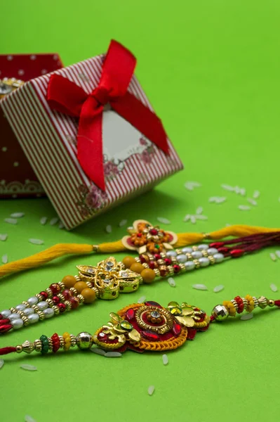Raakhi and a gift for the sister given by brother on the occasion of Raksha Bandhan. Indian festival Raksha Bandhan background with an elegant Rakhi on Green background. — Stock Photo, Image