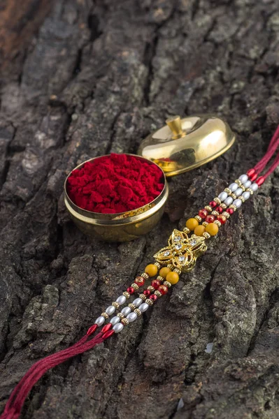 Indisches Festival: Raksha Bandhan Hintergrund mit einem eleganten Rakhi, Reiskörner und Kumkum. Ein traditionelles indisches Armband, das ein Symbol der Liebe zwischen Brüdern und Schwestern ist. — Stockfoto