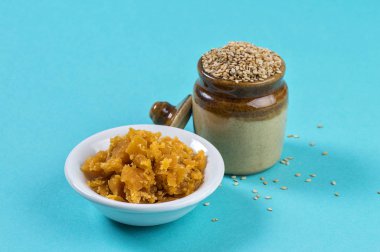 Çamurda susam tohumları, mavi arka planda kavanozda jaggery