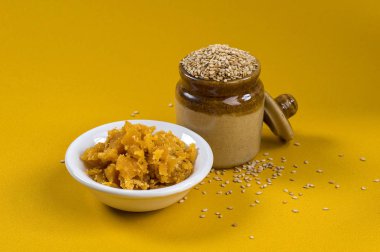 Susam tohumları kil kabın içinde Jaggery ise sarı arka planda