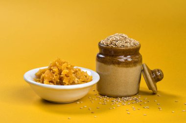 Susam tohumları kil kabın içinde Jaggery ise sarı arka planda