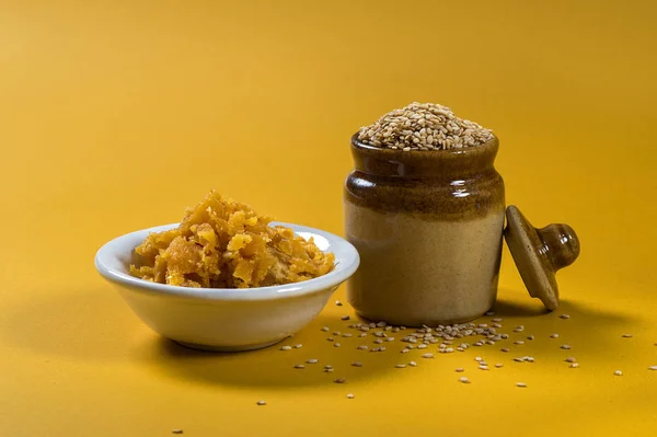 Sesame Seeds у глиняному горщику з Яггері в чаші на жовтому тлі — стокове фото