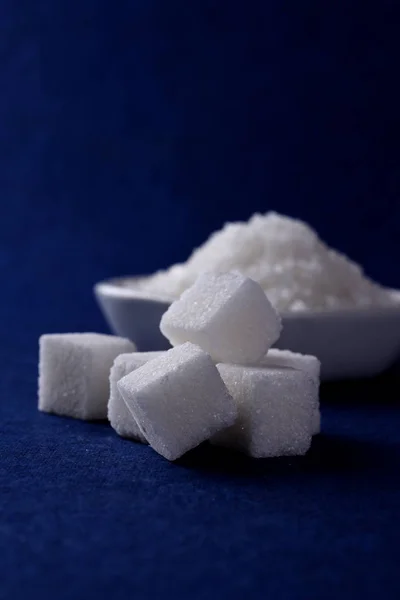 Сахарные кубики с сахаром в белой тарелке на синем фоне — стоковое фото