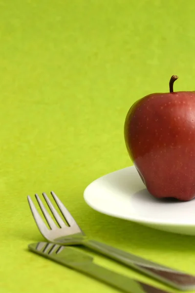Yeşil Arka Planda Çatal Bıçaklı Lezzetli Bir Elma — Stok fotoğraf