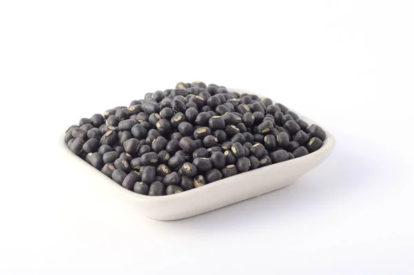 Urad dal, gramo negro, Vigna mungo en plato blanco sobre fondo blanco — Foto de Stock