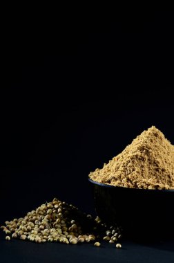 Kişniş tozu ve kişniş tohumları siyah arkaplanda