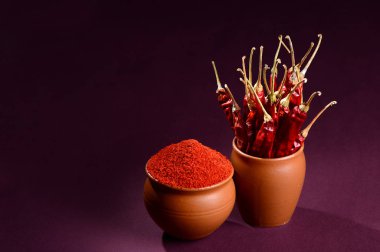 Kil çömleklerde kırmızı soğumuş biber, koyu arka planda kurutulmuş biber.