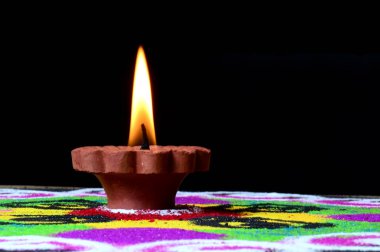 Arka planda Rangoli, Diwali kutlaması sırasında Clay diya lambaları yanıyor.