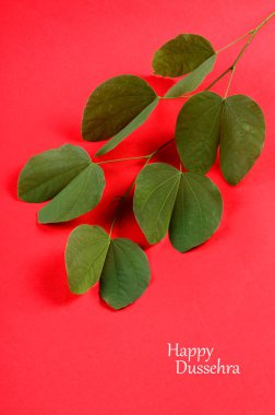 Indian Festival Dussehra, showing golden leaf on red background. Greeting card. clipart