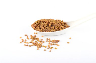 Beyaz arka planda izole edilmiş kaşıkta çemen otu tohumları