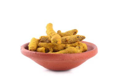 Beyaz arkaplanda izole edilmiş kil kapta kuru zerdeçal kökleri veya kabukları