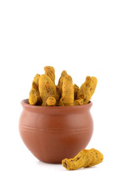 Beyaz arkaplanda izole edilmiş kil kapta kuru zerdeçal kökleri veya kabukları