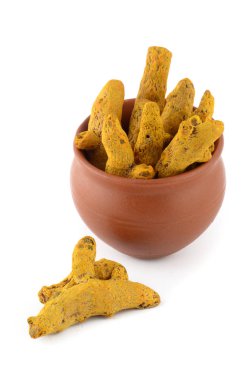 Beyaz arkaplanda izole edilmiş kil kapta kuru zerdeçal kökleri veya kabukları