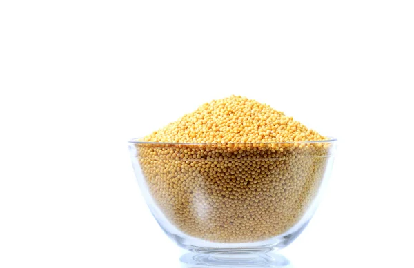 Gele mosterd zaden in glazen kom geïsoleerd op witte achtergrond — Stockfoto