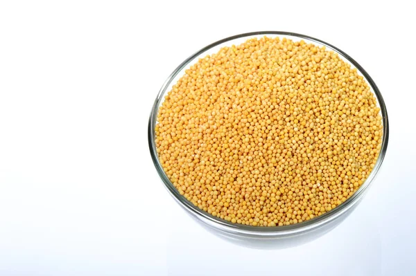 Yellow mustard seeds in glass bowl isolated on white background — Stock Photo, Image