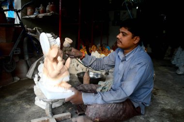 Mumbai, Maharashtra - 24 Ağustos 2014: Sanatçı Hindu tanrısı Ganesha 'nın bir putuna son rötuşları yapıyor. Ganesha festivali için bir atölye çalışması, 24 Ağustos 2014, Maharashtra, Hindistan.