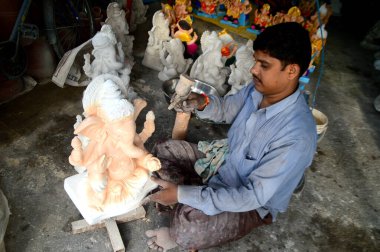 Mumbai, Maharashtra - 24 Ağustos 2014: Sanatçı Hindu tanrısı Ganesha 'nın bir putuna son rötuşları yapıyor. Ganesha festivali için bir atölye çalışması, 24 Ağustos 2014, Maharashtra, Hindistan.