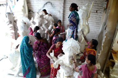 Mumbai, Maharashtra - 24 Ağustos 2014: Sanatçı Hindu tanrısı Ganesha 'nın bir putuna son rötuşları yapıyor. Ganesha festivali için bir atölye çalışması, 24 Ağustos 2014, Maharashtra, Hindistan.