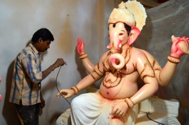 Mumbai, Maharashtra - 24 Ağustos 2014: Sanatçı Hindu tanrısı Ganesha 'nın bir putuna son rötuşları yapıyor. Ganesha festivali için bir atölye çalışması, 24 Ağustos 2014, Maharashtra, Hindistan.