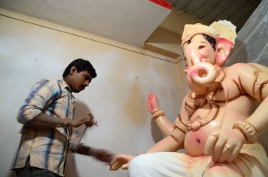 Mumbai, Maharashtra - 24 Ağustos 2014: Sanatçı Hindu tanrısı Ganesha 'nın bir putuna son rötuşları yapıyor. Ganesha festivali için bir atölye çalışması, 24 Ağustos 2014, Maharashtra, Hindistan.