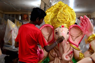 Mumbai, Maharashtra - 24 Ağustos 2014: Sanatçı Hindu tanrısı Ganesha 'nın bir putuna son rötuşları yapıyor. Ganesha festivali için bir atölye çalışması, 24 Ağustos 2014, Maharashtra, Hindistan.