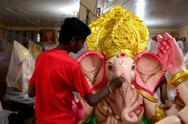Mumbai, Maharashtra - 24 Ağustos 2014: Sanatçı Hindu tanrısı Ganesha 'nın bir putuna son rötuşları yapıyor. Ganesha festivali için bir atölye çalışması, 24 Ağustos 2014, Maharashtra, Hindistan.