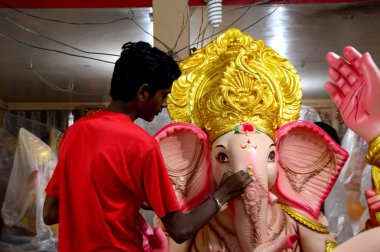 Mumbai, Maharashtra - 24 Ağustos 2014: Sanatçı Hindu tanrısı Ganesha 'nın bir putuna son rötuşları yapıyor. Ganesha festivali için bir atölye çalışması, 24 Ağustos 2014, Maharashtra, Hindistan.