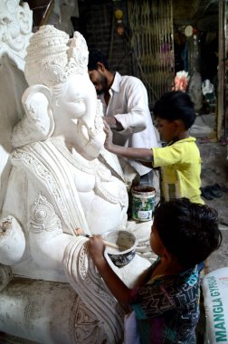 Mumbai, Maharashtra - 24 Ağustos 2014: Sanatçı Hindu tanrısı Ganesha 'nın bir putuna son rötuşları yapıyor. Ganesha festivali için bir atölye çalışması, 24 Ağustos 2014, Maharashtra, Hindistan.