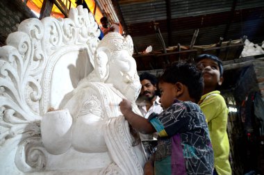 Mumbai, Maharashtra - 24 Ağustos 2014: Sanatçı Hindu tanrısı Ganesha 'nın bir putuna son rötuşları yapıyor. Ganesha festivali için bir atölye çalışması, 24 Ağustos 2014, Maharashtra, Hindistan.