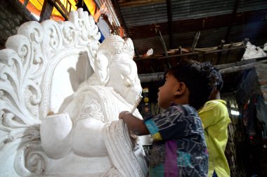Mumbai, Maharashtra - 24 Ağustos 2014: Sanatçı Hindu tanrısı Ganesha 'nın bir putuna son rötuşları yapıyor. Ganesha festivali için bir atölye çalışması, 24 Ağustos 2014, Maharashtra, Hindistan.