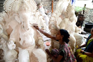 Mumbai, Maharashtra - 24 Ağustos 2014: Sanatçı Hindu tanrısı Ganesha 'nın bir putuna son rötuşları yapıyor. Ganesha festivali için bir atölye çalışması, 24 Ağustos 2014, Maharashtra, Hindistan.