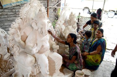 Mumbai, Maharashtra - 24 Ağustos 2014: Sanatçı Hindu tanrısı Ganesha 'nın bir putuna son rötuşları yapıyor. Ganesha festivali için bir atölye çalışması, 24 Ağustos 2014, Maharashtra, Hindistan.