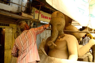 Nagpur, Maharashtra - 3 Ağustos 2014: Sanatçı 3 Ağustos 2014 'te Hindistan' ın Maharashtra kentinde Ganesha-Festivali için bir sanatçı atölyesinde Hindu tanrısı Lord Ganesha 'nın bir putuna son rötuşlarını yaptı..